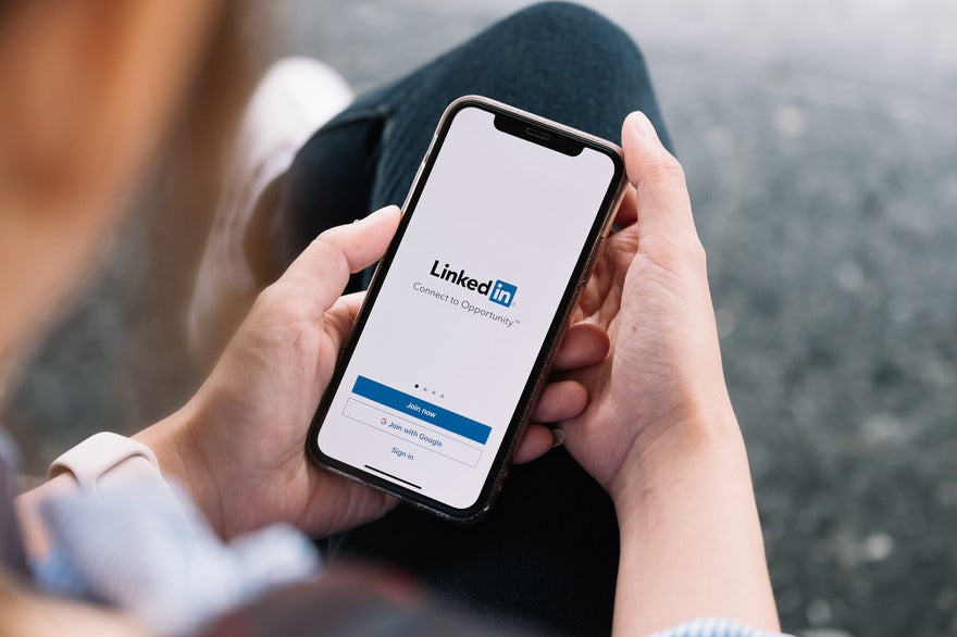 Person holding a phone with the LinkedIn sign up page on the screen