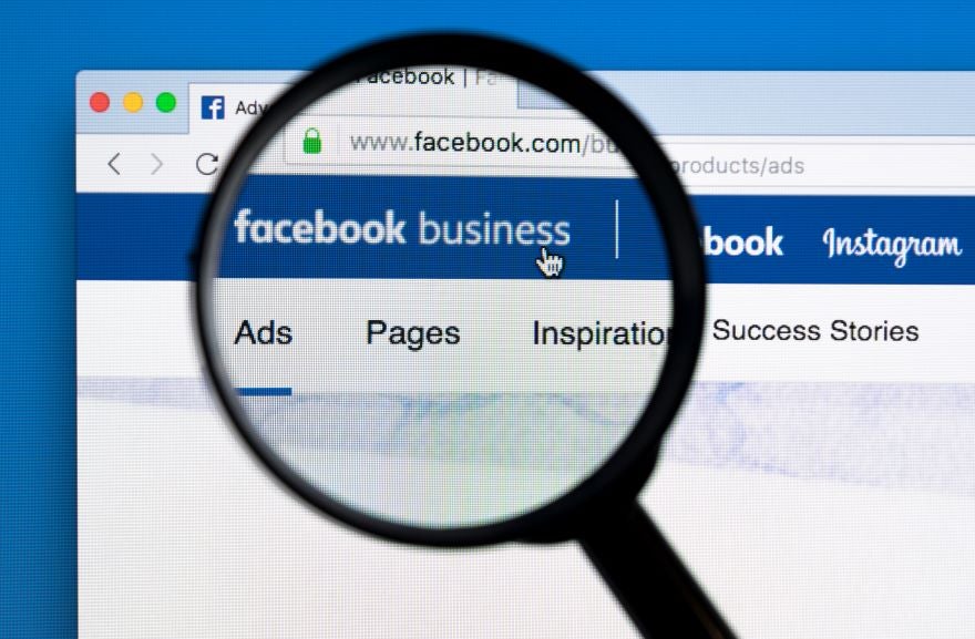 A magnifying glass positioned over a monitor with "Facebook Business" on screen