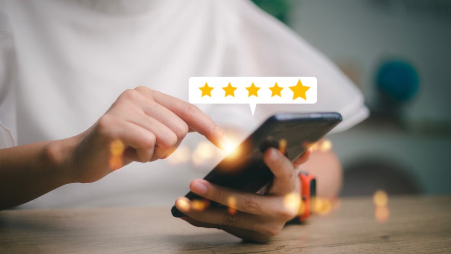 Person using a phone with a floating image above showing a five star rating