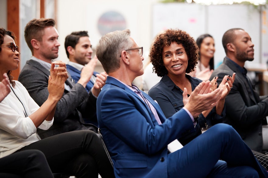 Businessmen and women sat down at a conference and clapping