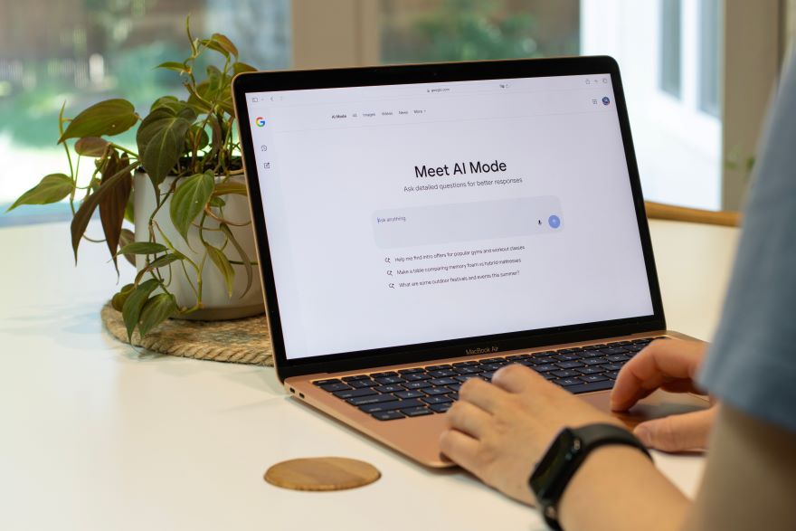 Hands typing on a laptop with the Google AI Mode landing page on screen
