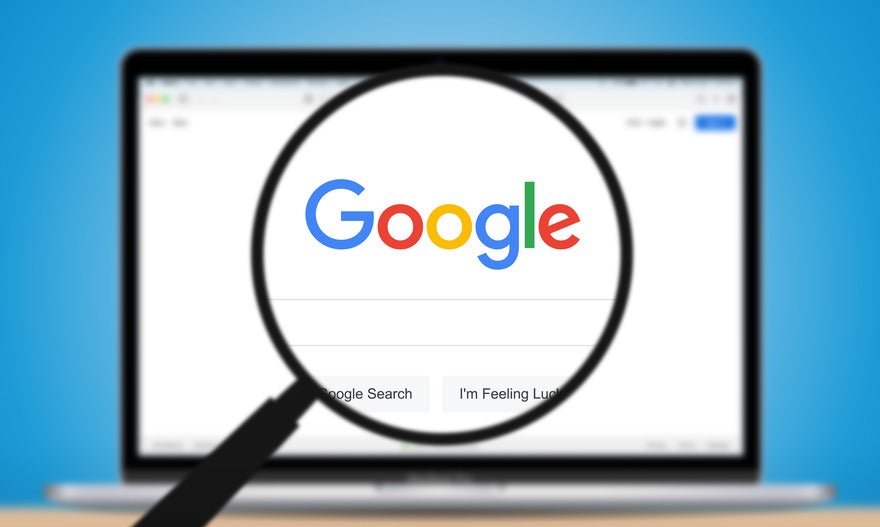 Magnifying glass hovering over a laptop screen showing the Google search homepage