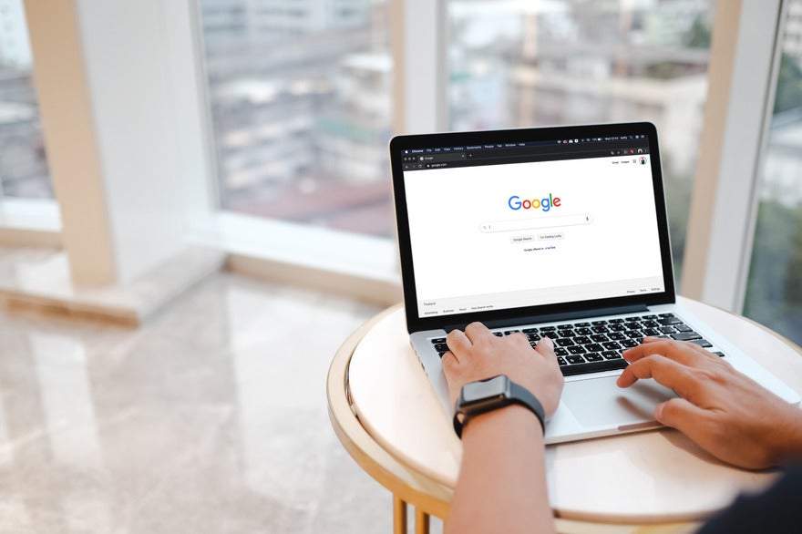 Person typing at a laptop showing the Google homepage