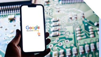 A hand holds a smartphone displaying the Google Reviews logo against a blurred circuit board background.