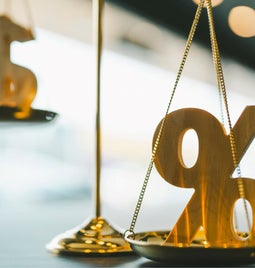 A percentage sign and a dollar sign on gold scales