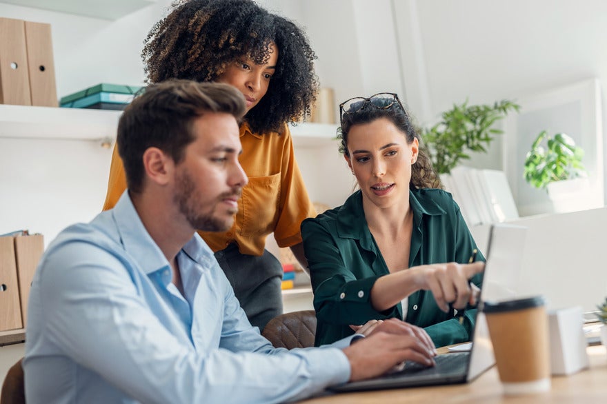 Three people working around a laptop together