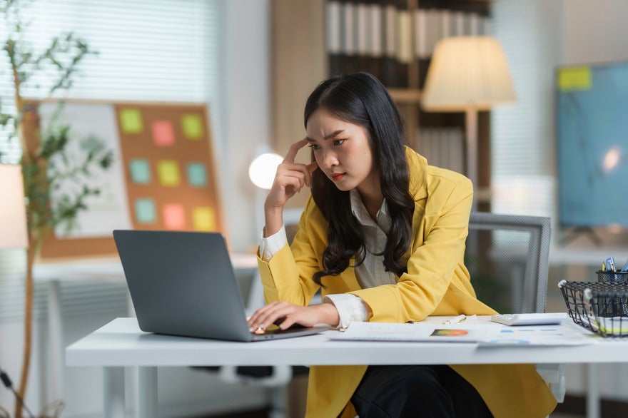 Woman looking puzzled and frustrated as she looks at a laptop