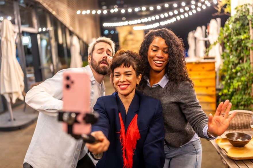 Three people posting in front of a phone on a tripod