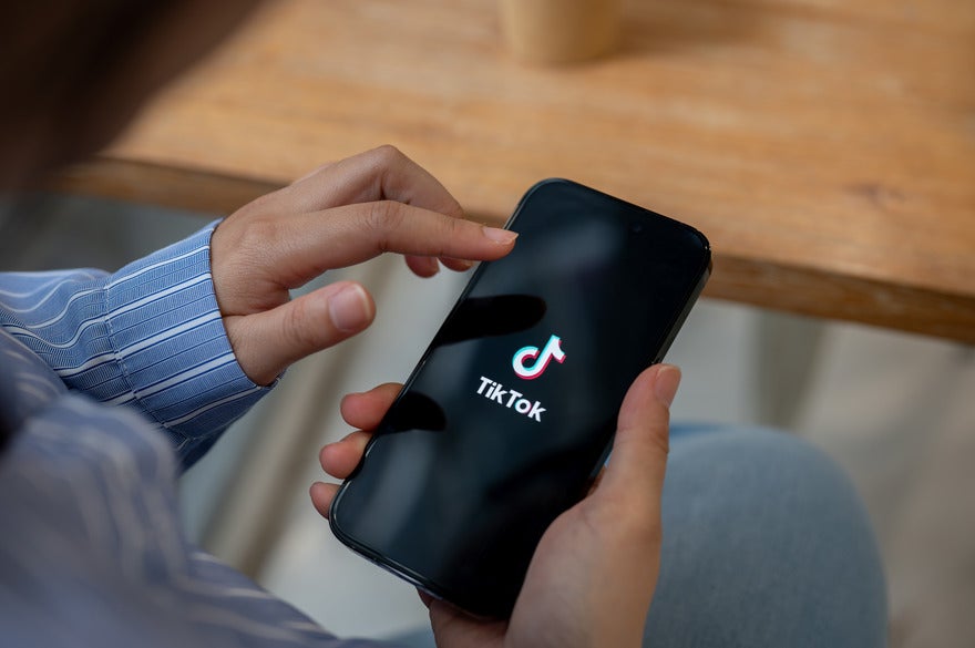 Person holding a phone with the TikTok logo on display