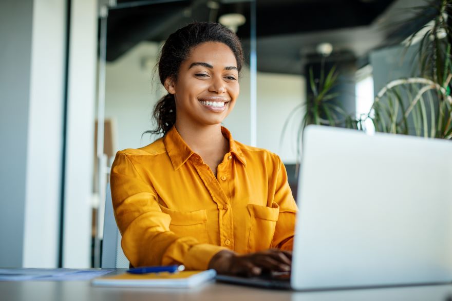 A woman smiling at her laptop
