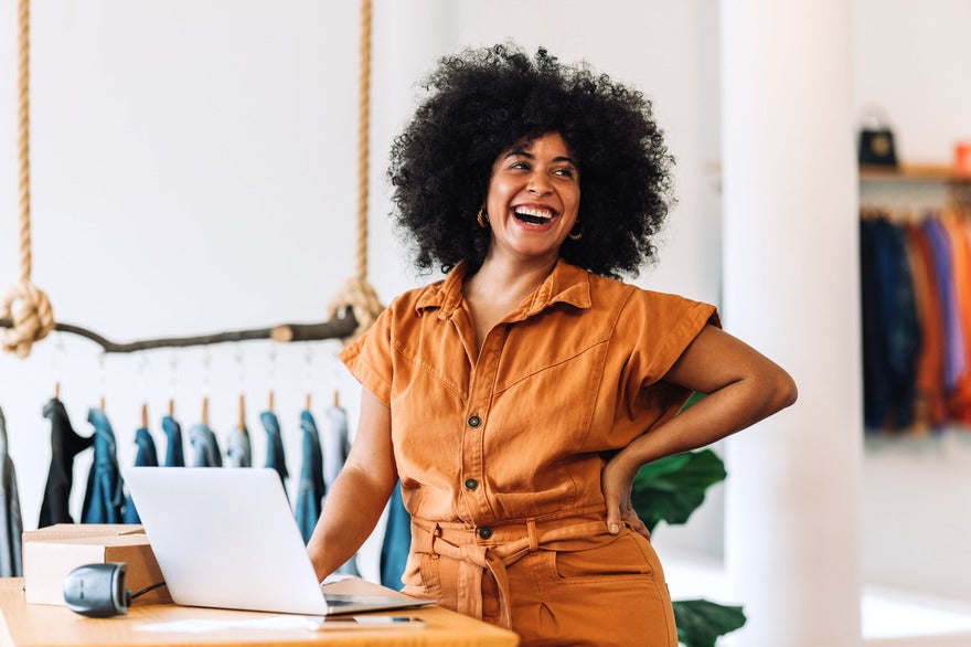 Women laughing as she stands next to her laptop