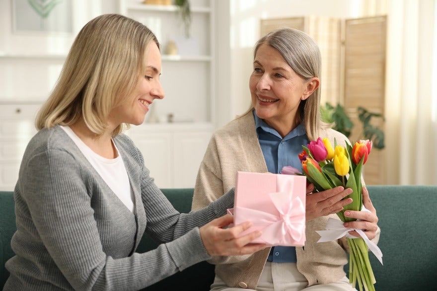 Daughter sharing gifts and flowers with her mother for Mother's Day