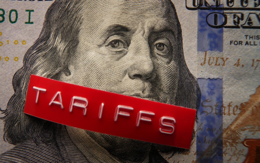 US money with a printed label on top saying tariffs