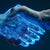 Human hand shaking a glowing blue hand to symbolize technology and AI