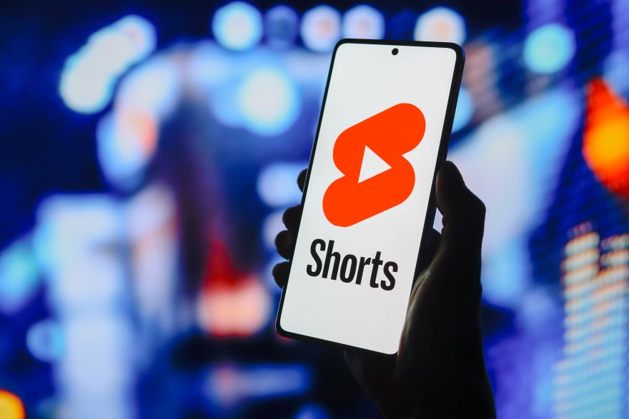 Photo of a hand holding a phone with the YouTube Shorts logo on screen