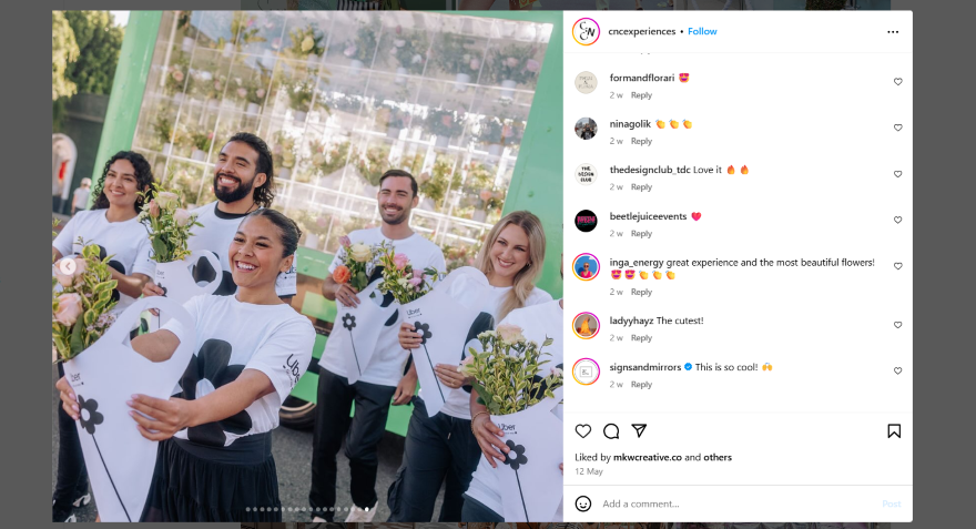 An Instagram post of a group of individuals in matching white t-shirts holds colorful flower arrangements in front of a vibrant green background.
